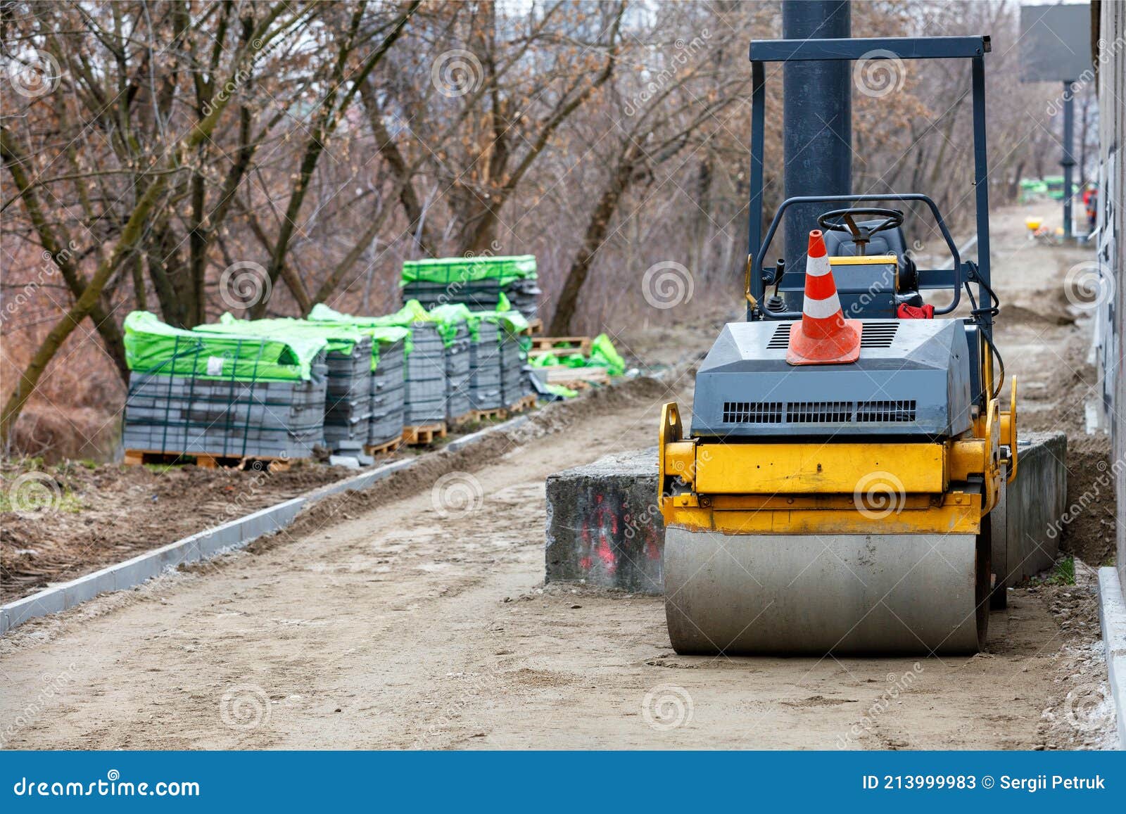 A Road Roller on a Fenced Building Site with a Sidewalk Under