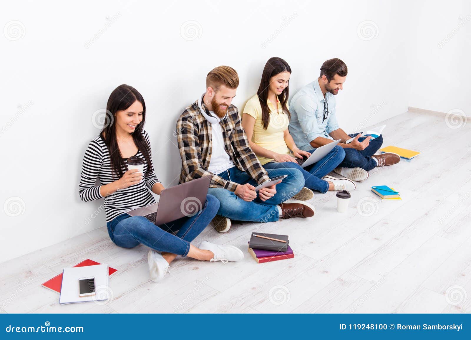 Company Of Happy Students Sitting On The Floor With Crossed Legs
