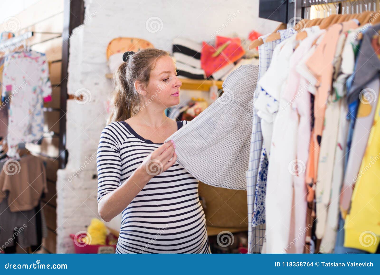 Compras De La Mujer Embarazada En La Tienda De Ropa Para Los Bebés Foto de archivo - Imagen de inglés, 118358764
