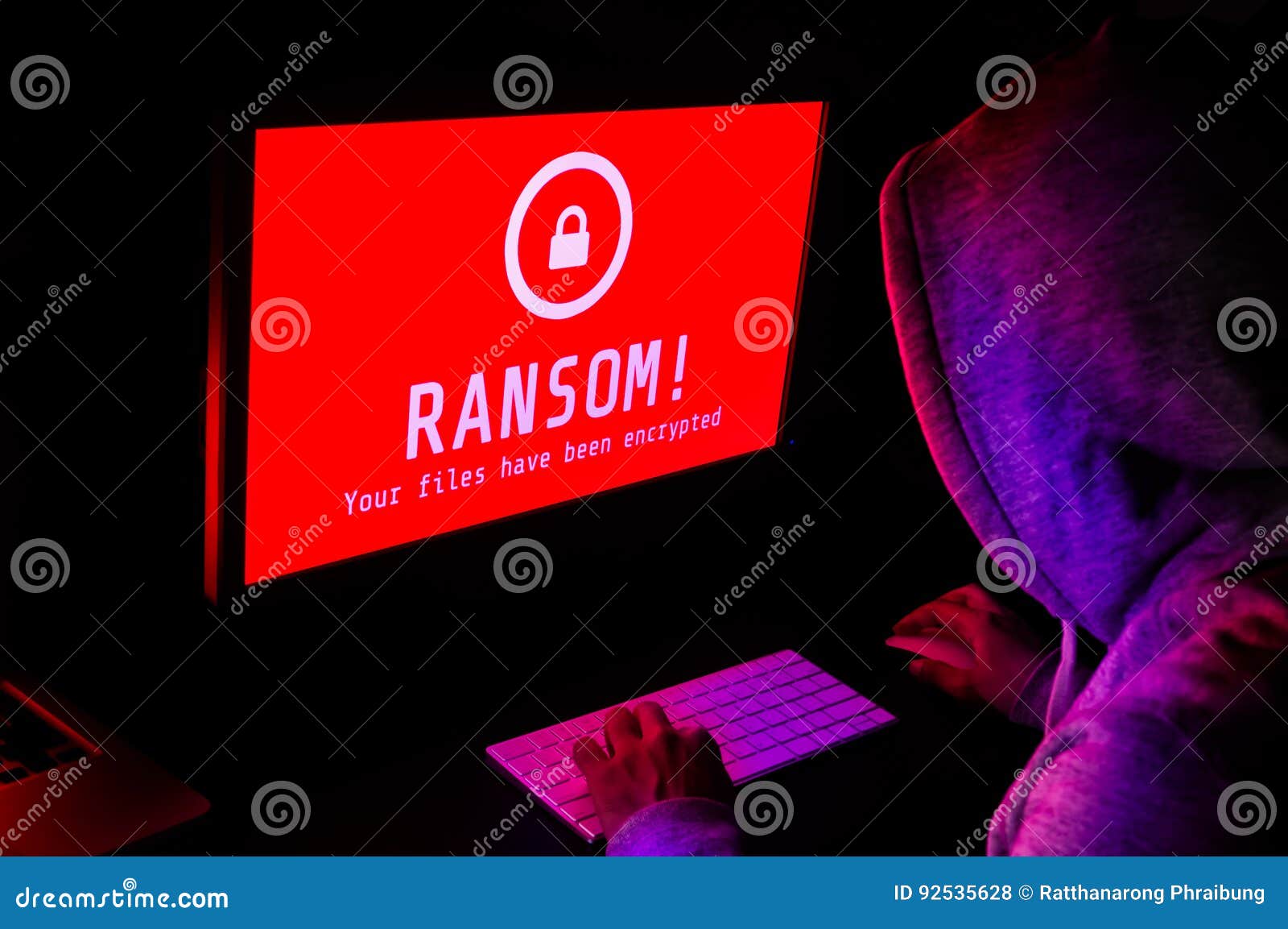 computer screen with ransomware attack alerts in red and a hacker man keying on keyboard in a dark room, ideal for online