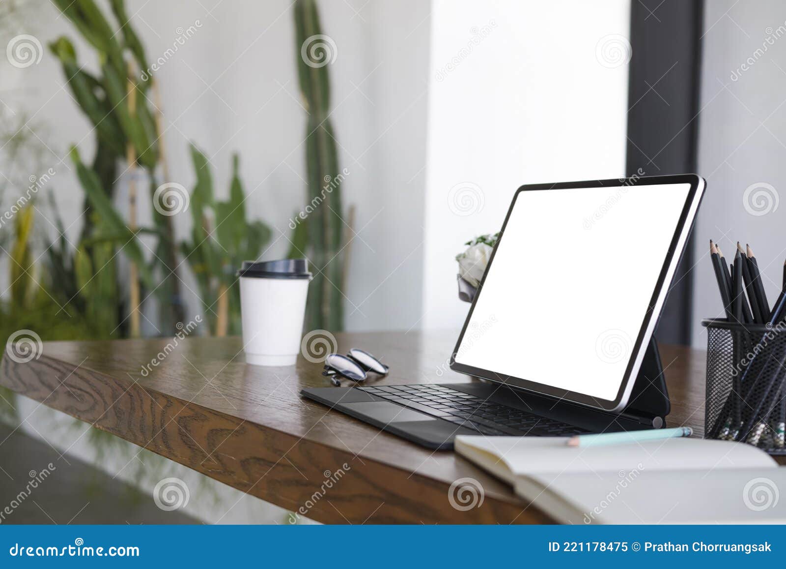 Tablet, Notebook, Coffee Cup and Pencil Holder on Wooden Table. Stock