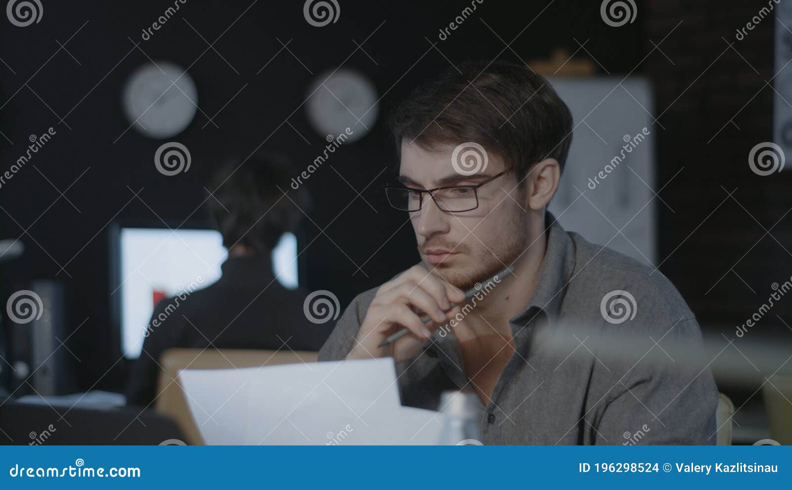 concentrated business analyst watching document and laptop screen in dark office