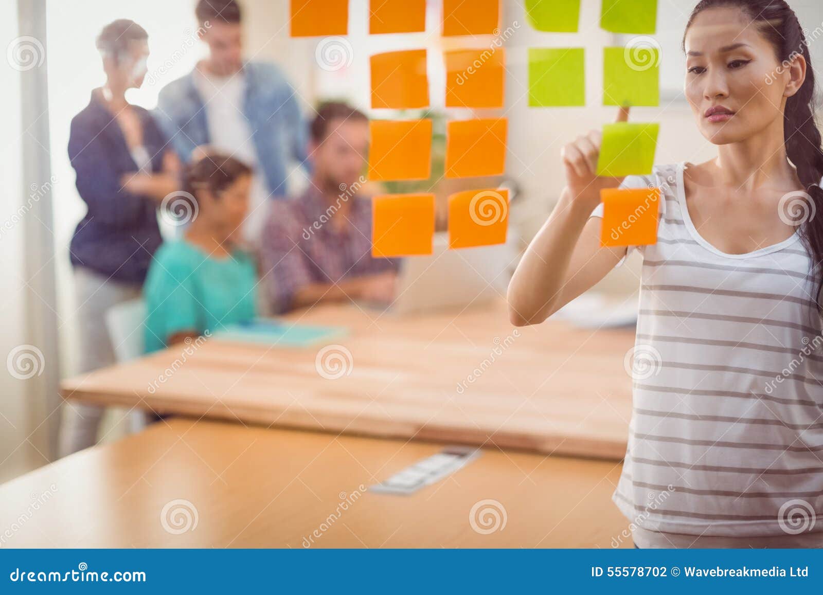 Concentrated Businesswoman Pointing Post Its on the Wall Stock Photo