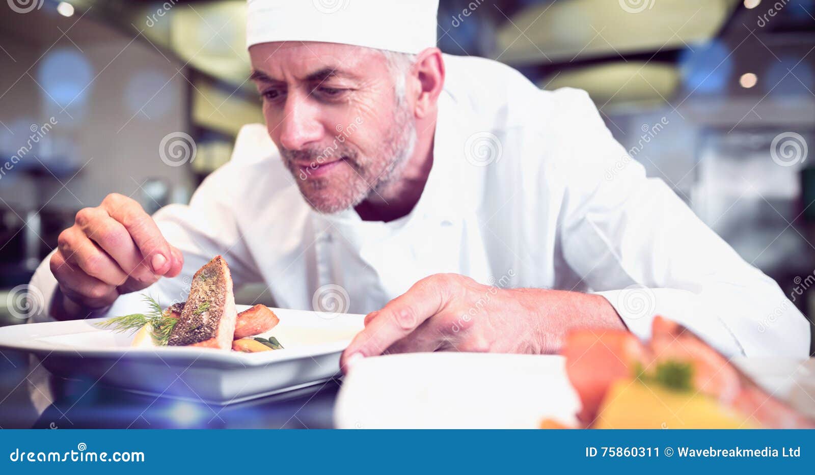 concentrated male chef garnishing food in kitchen