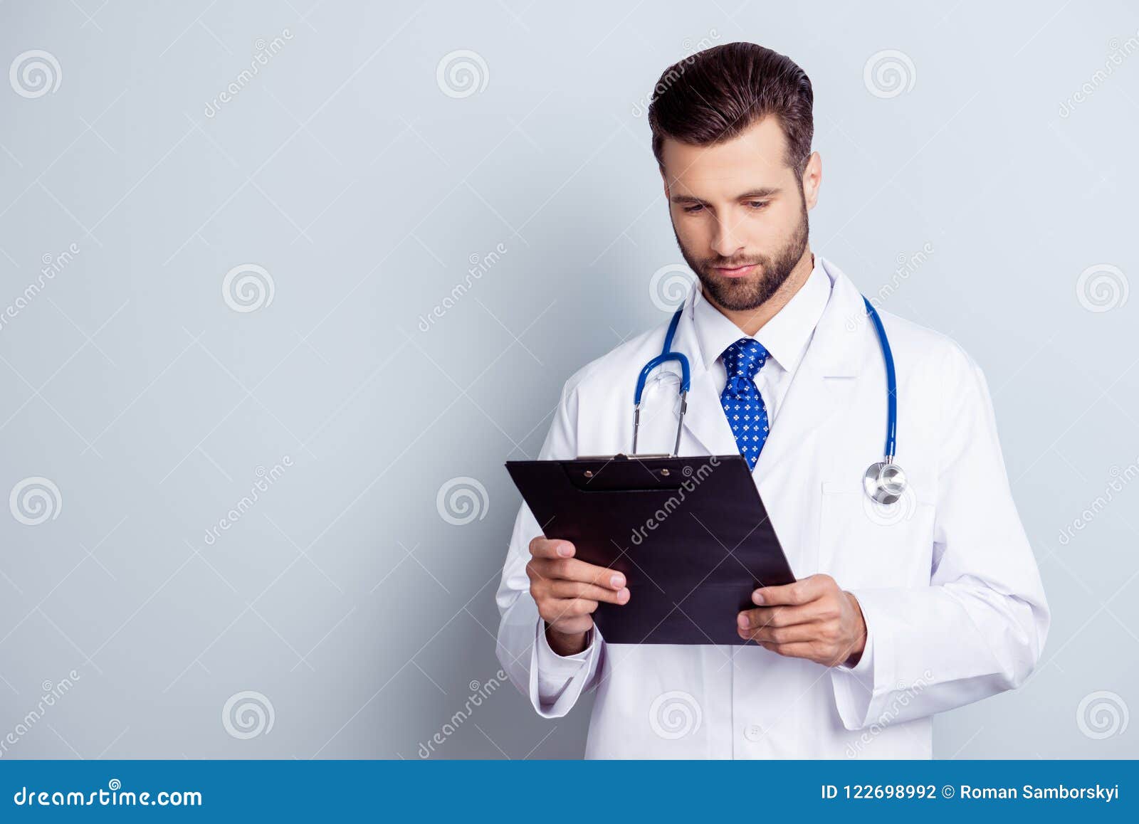 concentrated medico in uniform holding clipboard and reading inf