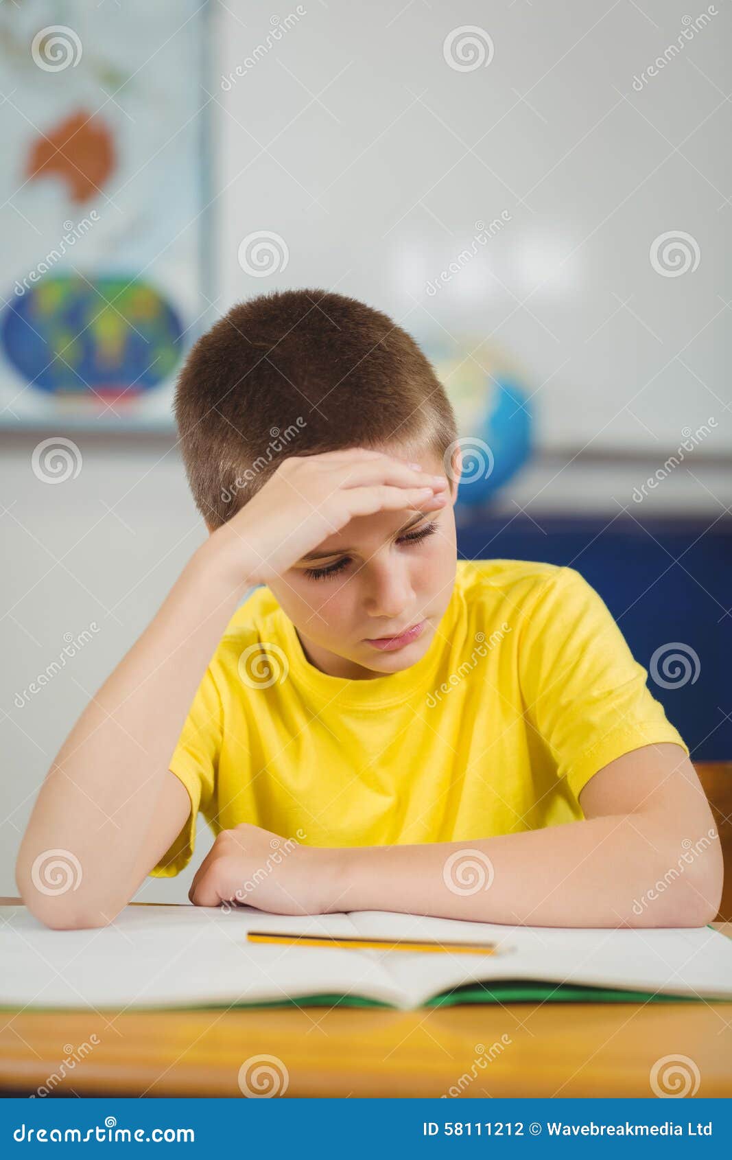 Concentrated Pupil Working at His Desk in a Classroom Stock Photo