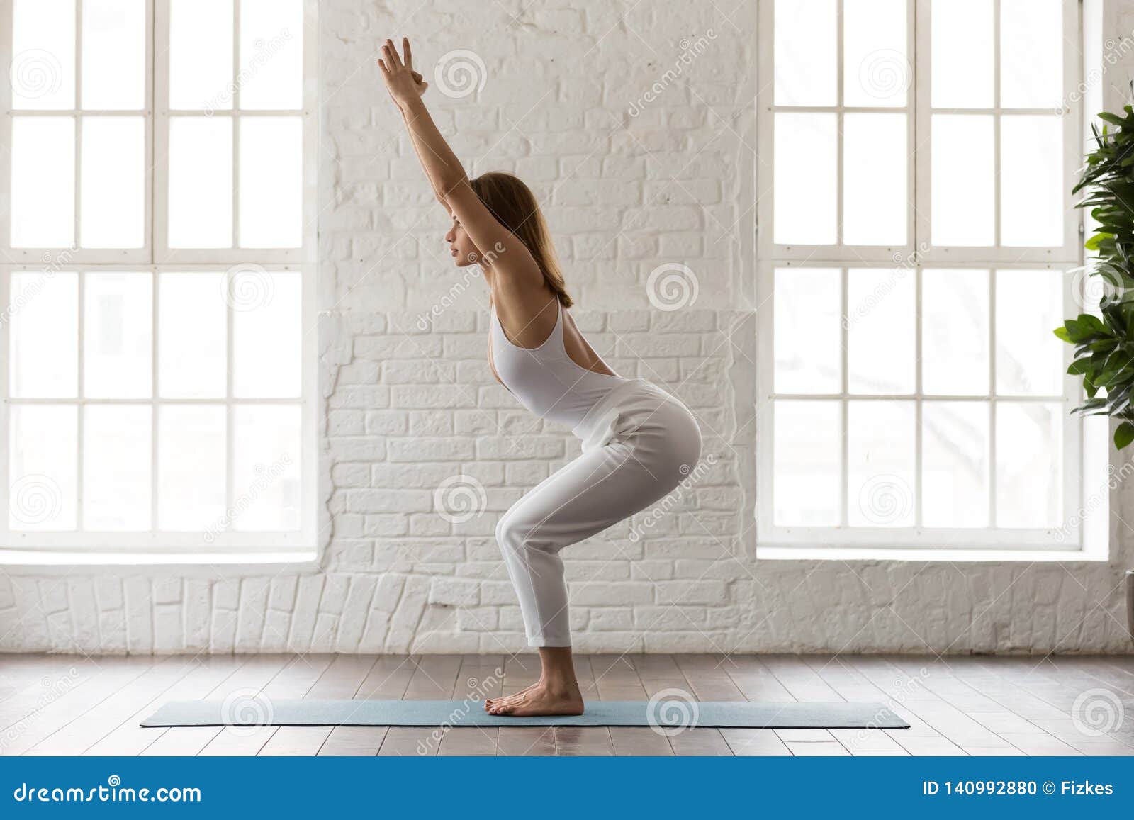 Iyengar yoga. Fit caucasian woman in purple leggings practice warrior pose  using a chair, isolated on white. Stock Photo