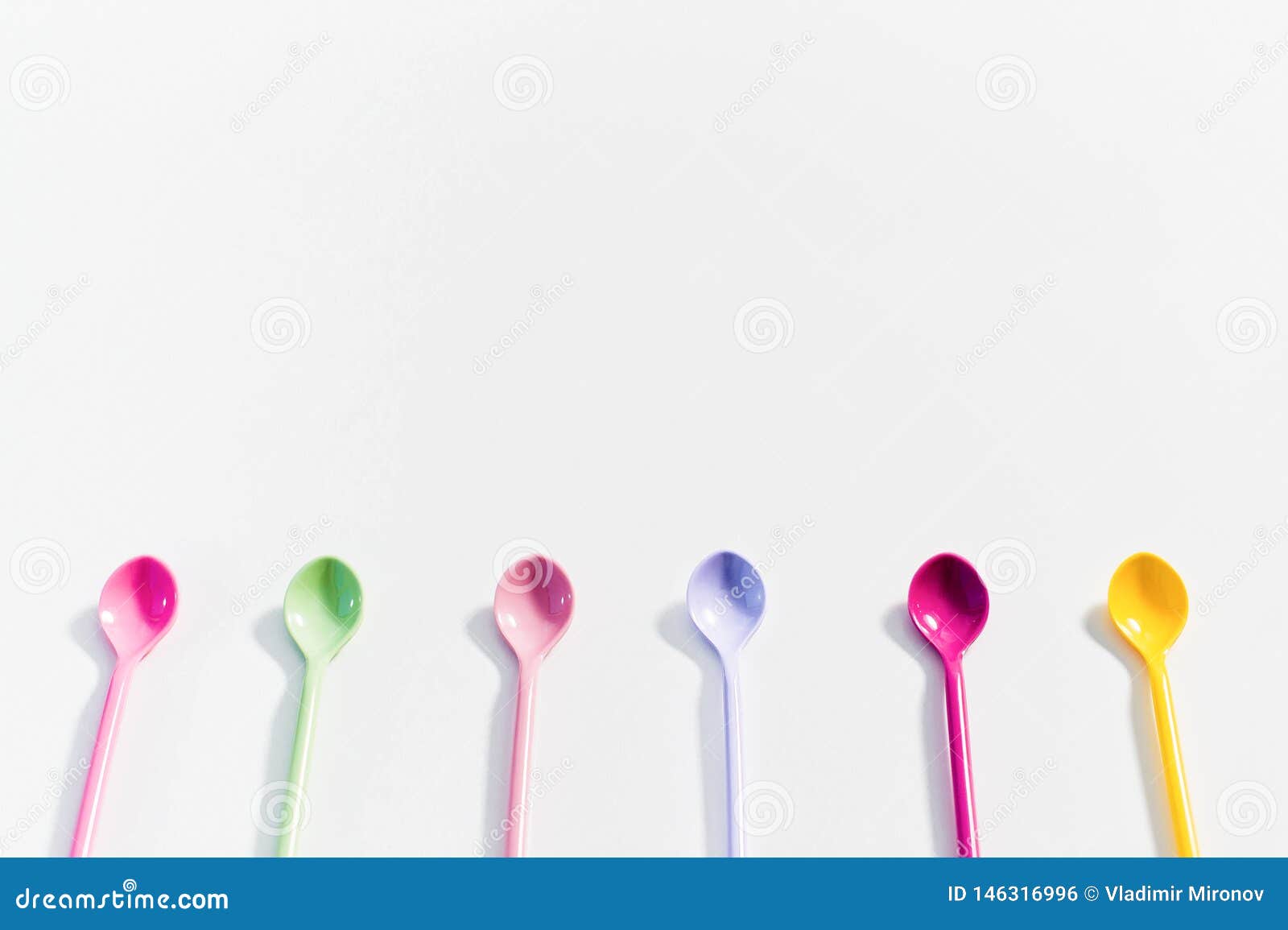The Concept of Coloured Dessert Spoons on White Background. Stock Photo