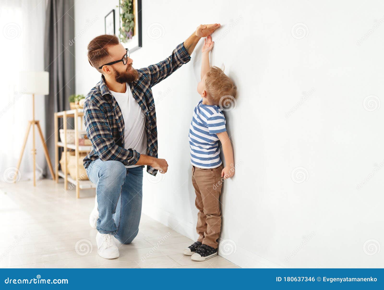 concept of development, growing up. father measures height of his young child son