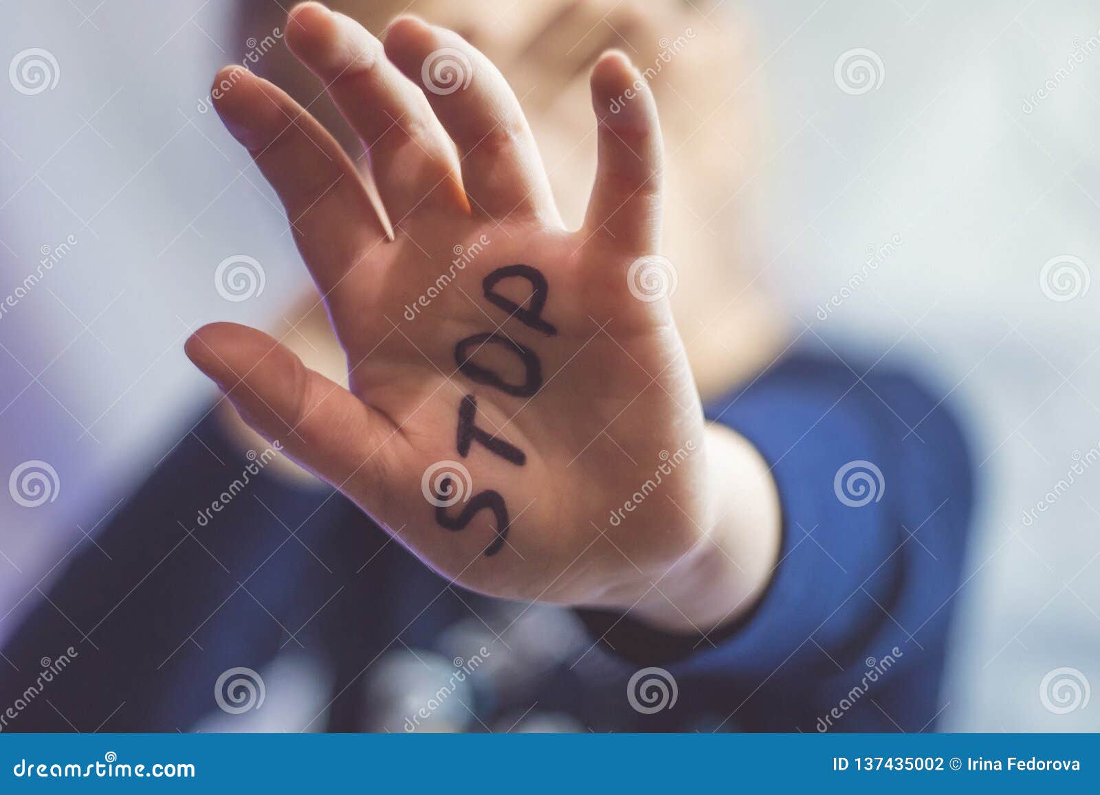 little frightened girl shows the word stop written on the arm. children are subjected to violence and publishing in the home and s