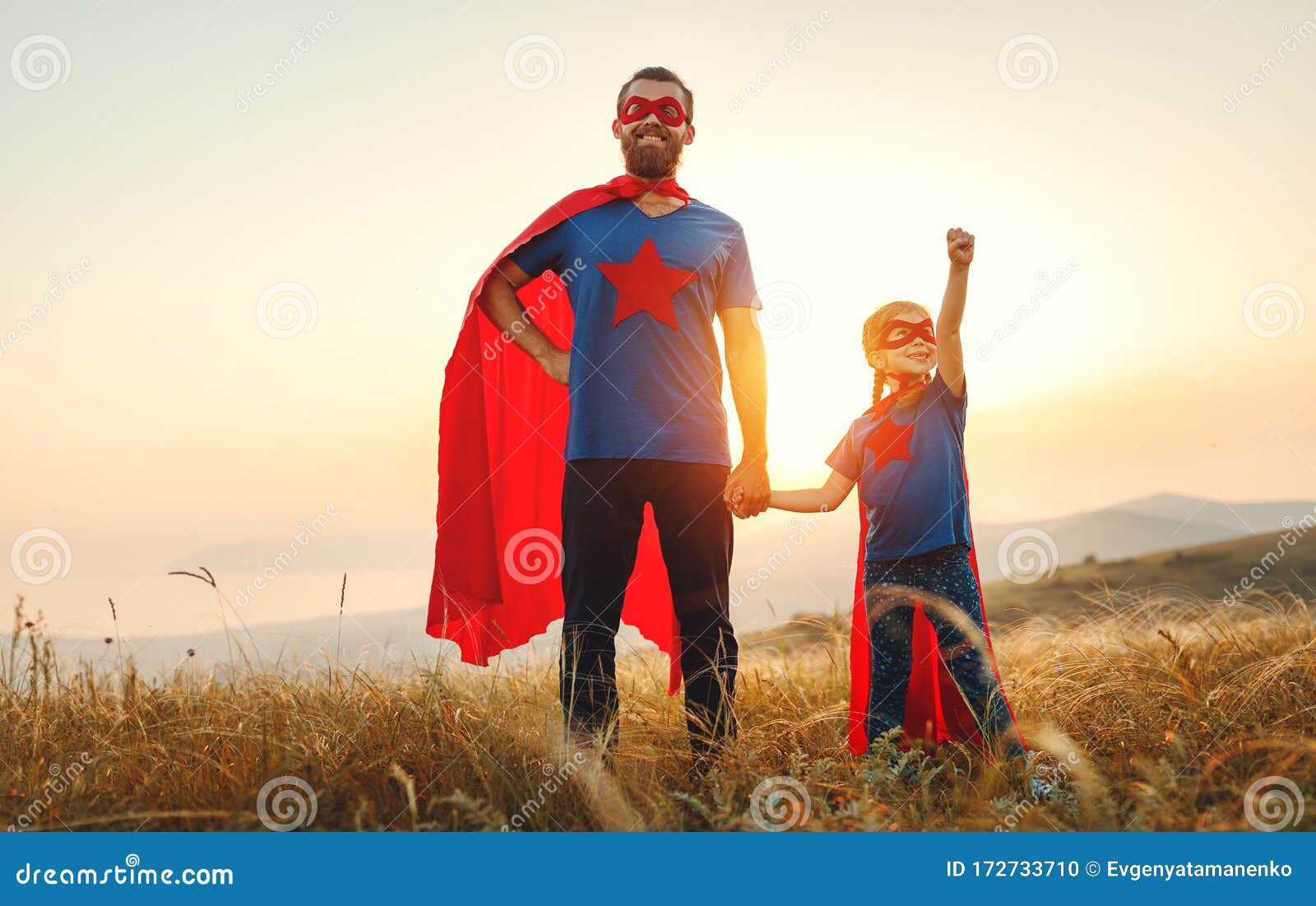 concept of father`s day. dad and child daughter in hero superhero costume at sunset