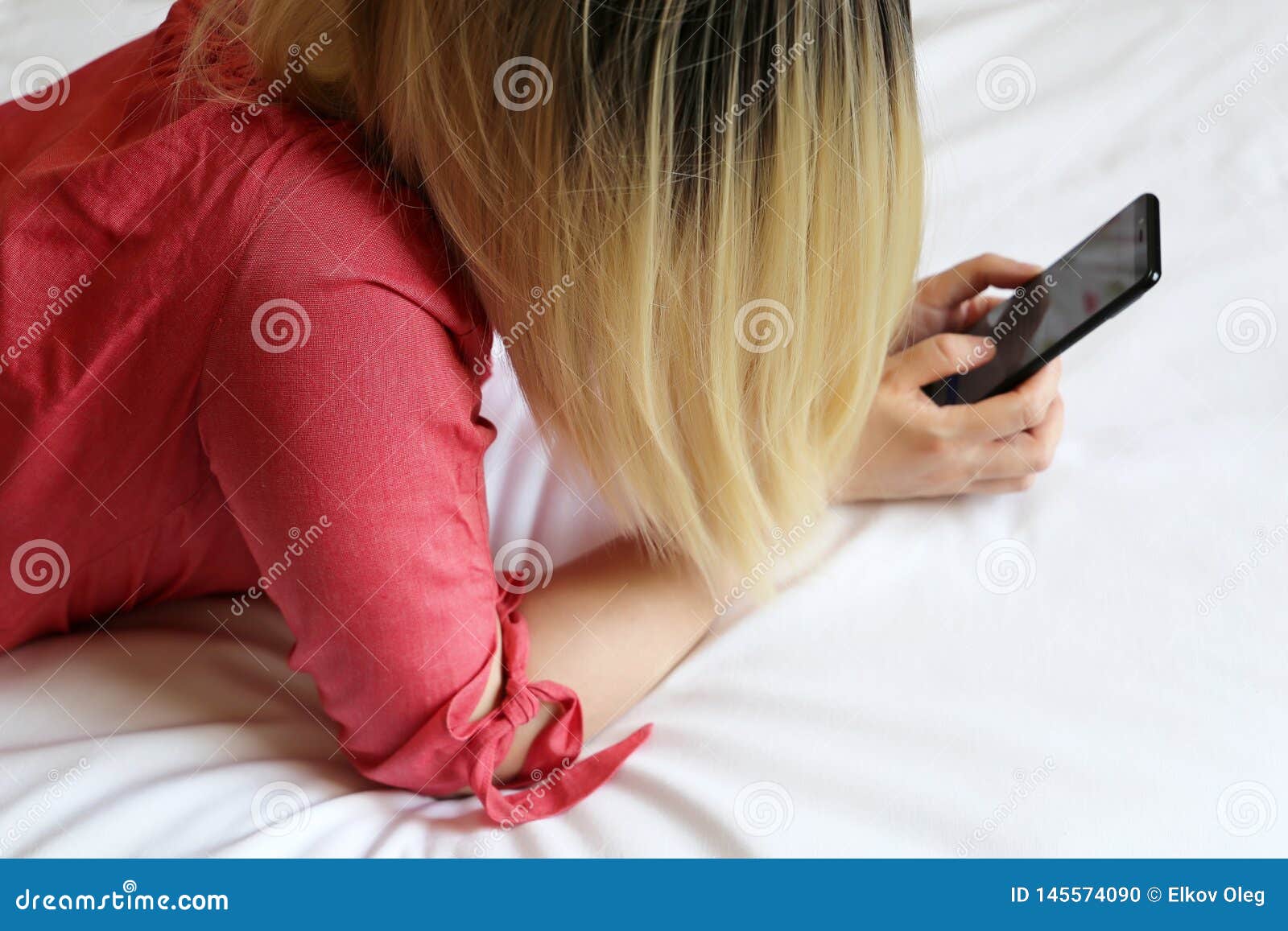 Blonde Woman with Smartphone Laying on the Bed, Girl Using Mobile Phone at Home Stock Photo pic