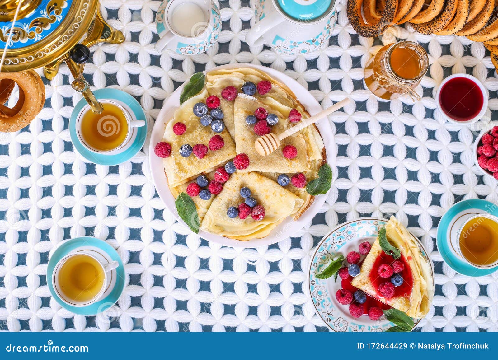 the concept of russian tea party at holiday maslenitsa, shrovetide. delicious russian pancakes with raspberry jam and berries. tea