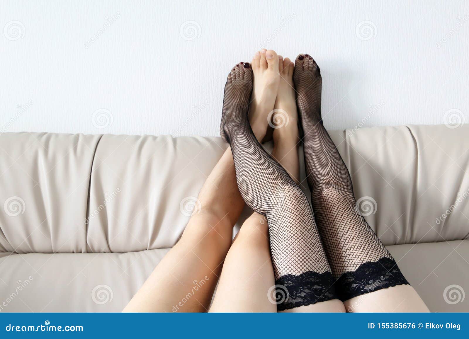 Couple in a Bedroom, Naked Male and Female Legs in Fishnet Stockings on Back of a Bed Stock Photo photo