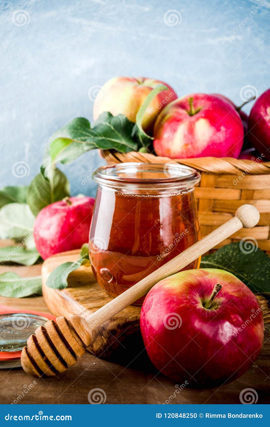 Concepto de Rosh HaShanah. Día de fiesta judío Rosh Hashanah o concepto del día de banquete de la manzana, con las manzanas, las hojas de la manzana y la miel rojas en el espacio del tarro, azul claro y de madera del fondo de la copia