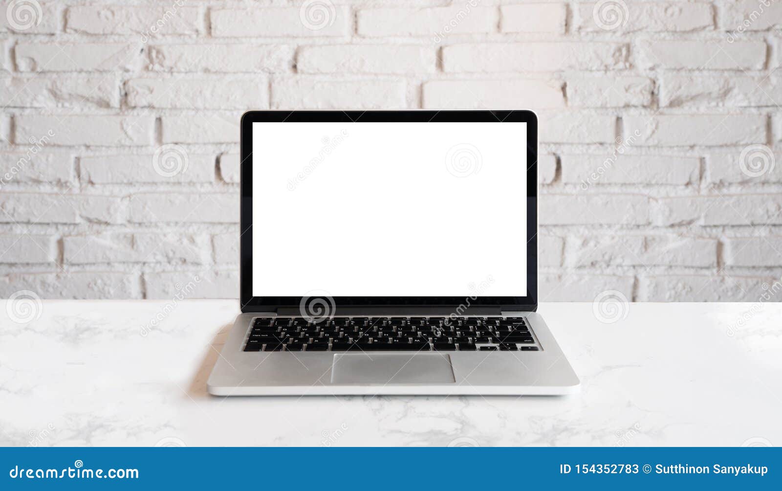 conceptual workspace, laptop computer with blank white screen. mock up laptop on wood table and white brick wall.