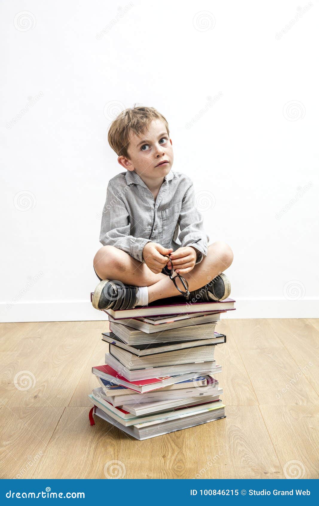 concerned small gifted kid sitting on books for school learning