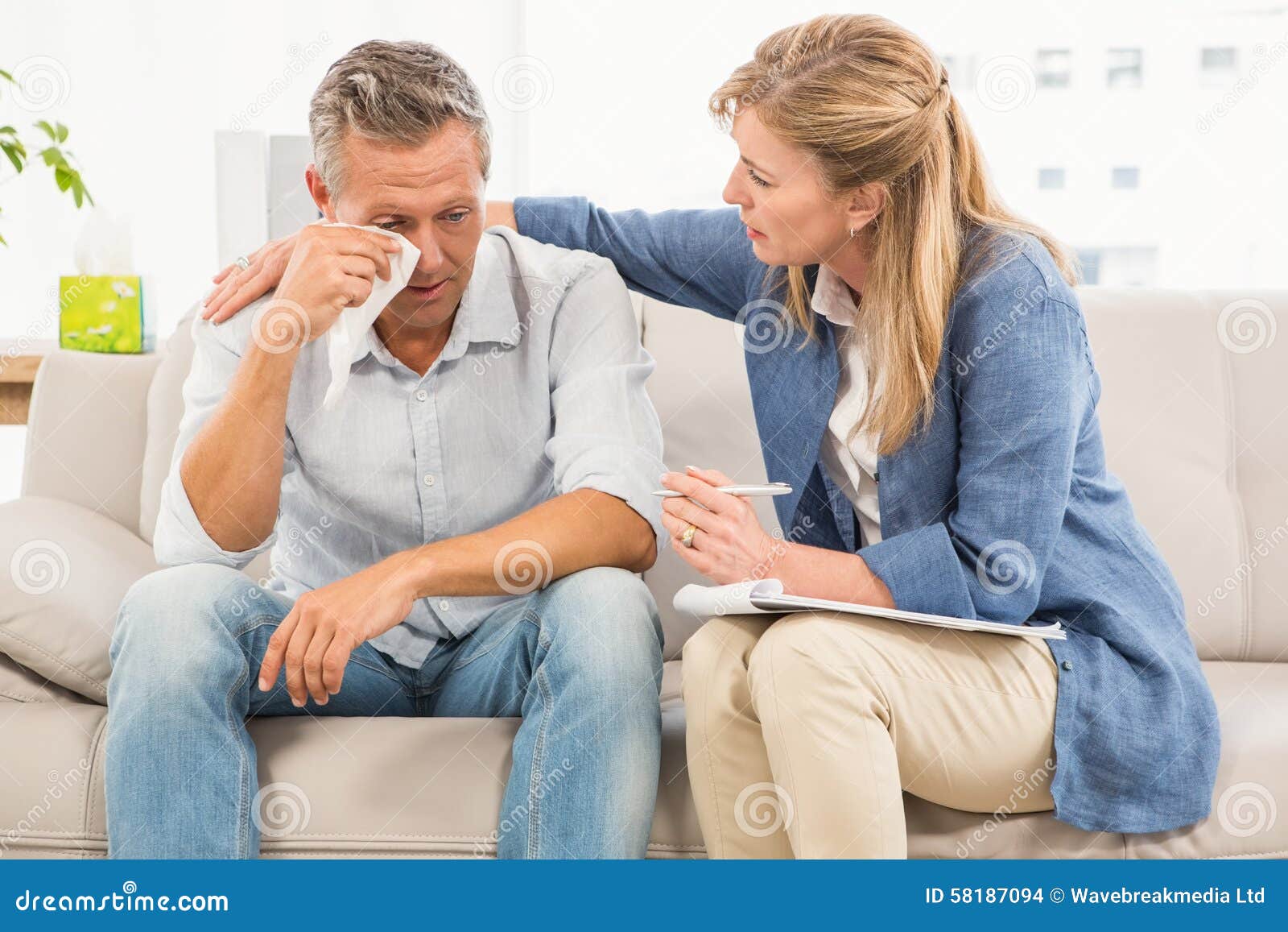 Concerned therapist comforting crying male patient in the office