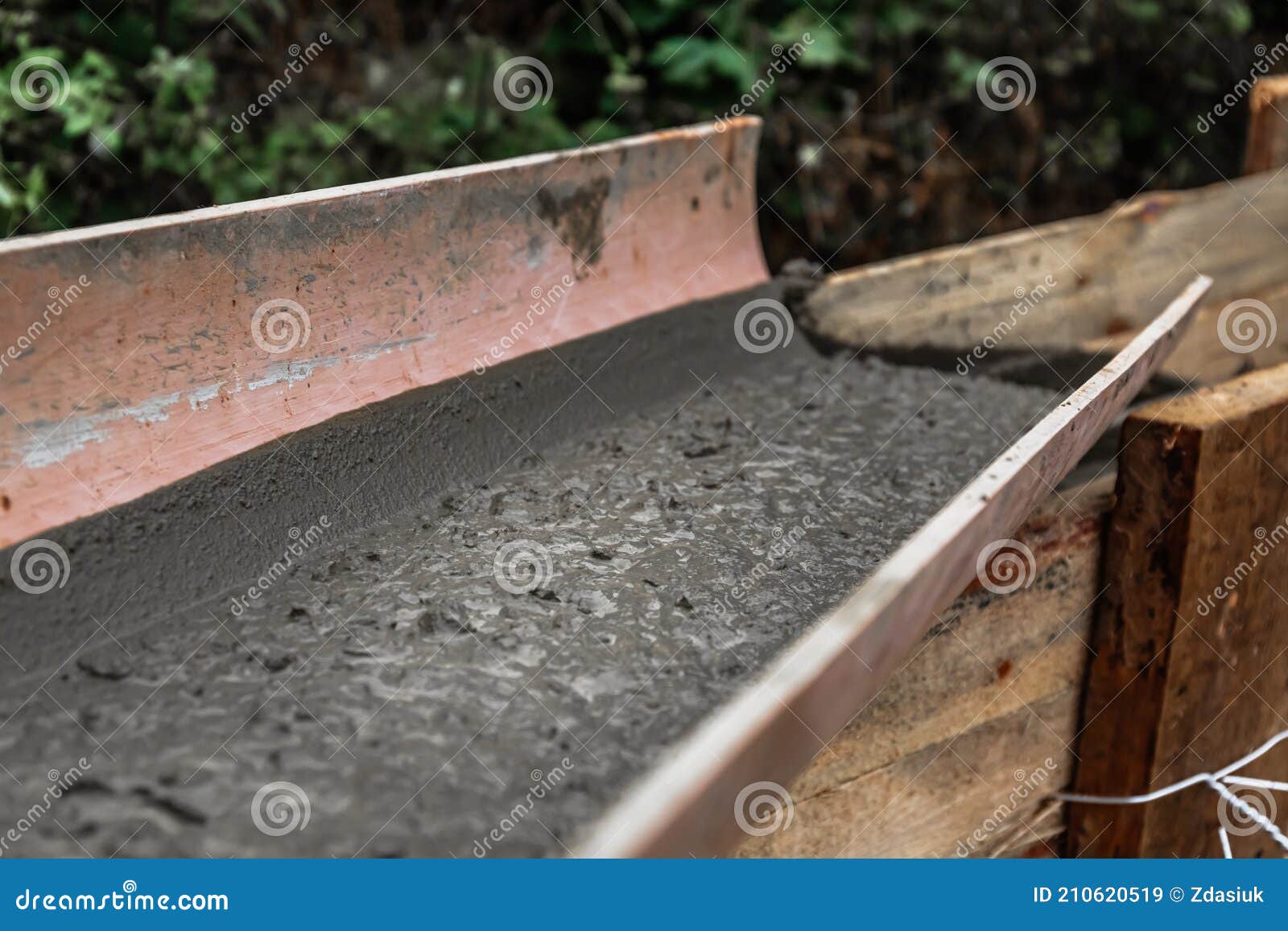 The Concrete Mixer Unloads the Concrete through a Chute into a Timber