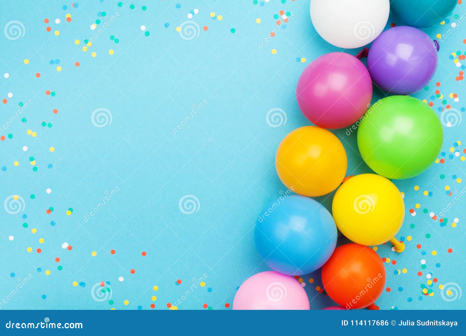 confetti and colorful balloons for birthday party on blue table top view. flat lay style.