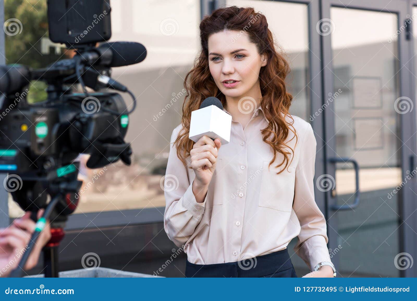Confident Anchorwoman with Microphone Standing in Front of Digital