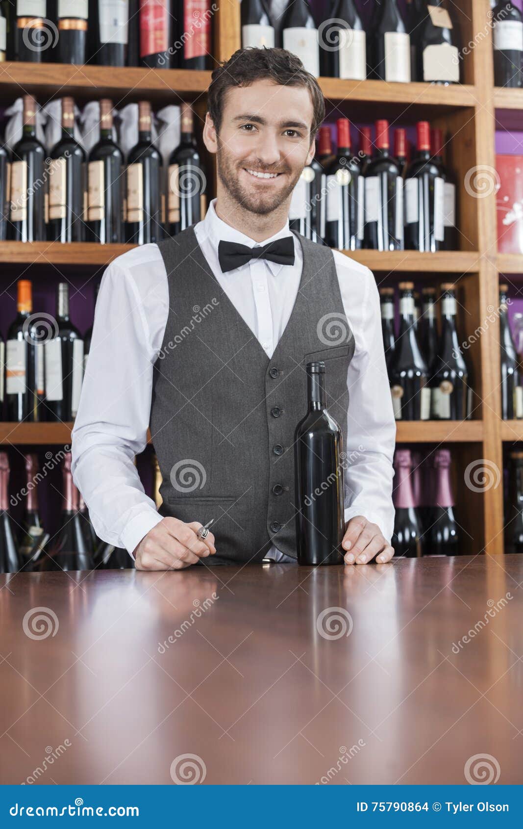 Confident Bartender with Wine Bottle Standing at Counter Stock Photo