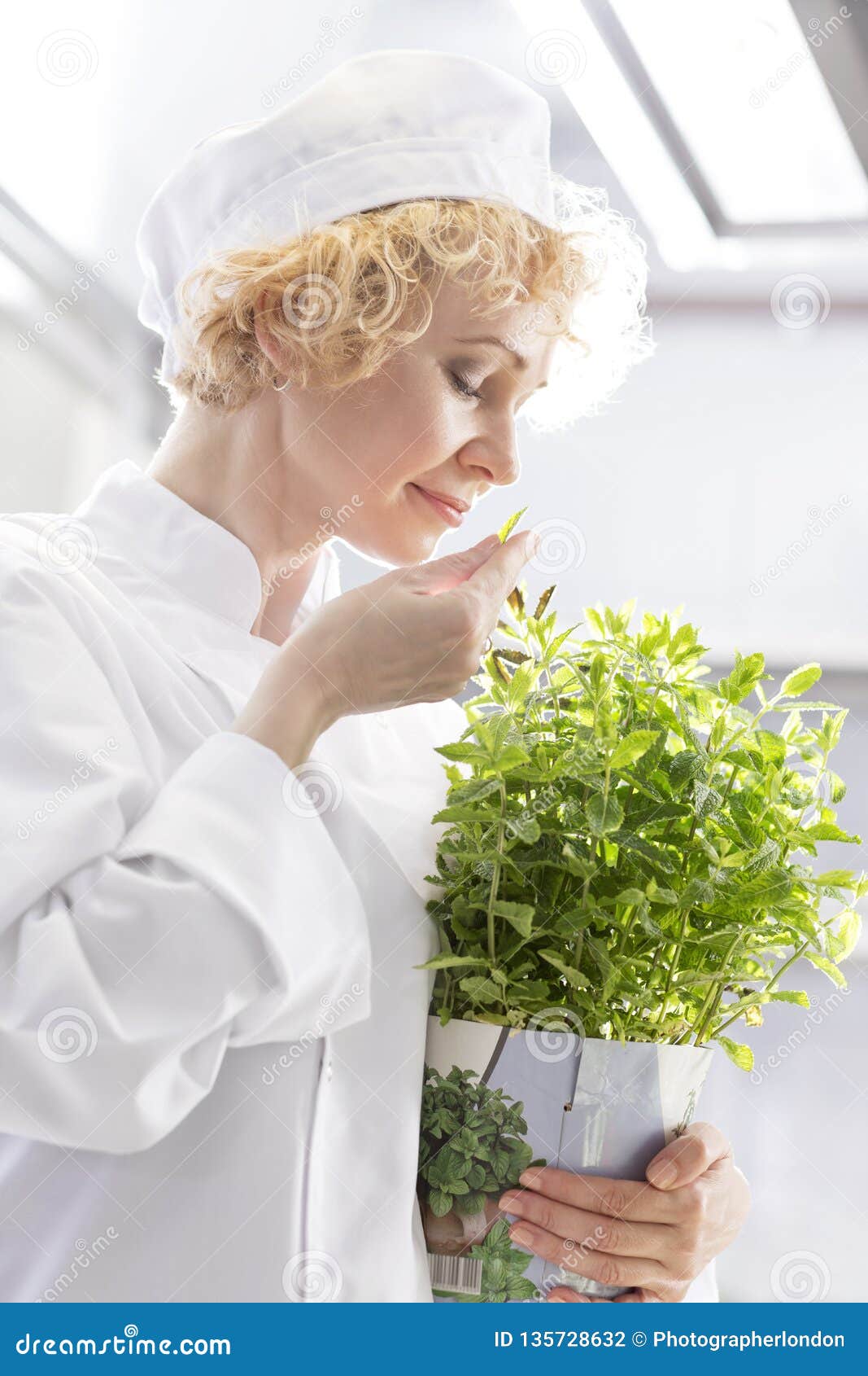 Confident Blond Chef Smelling Fresh Mint Leaf in Kitchen at Restaurant