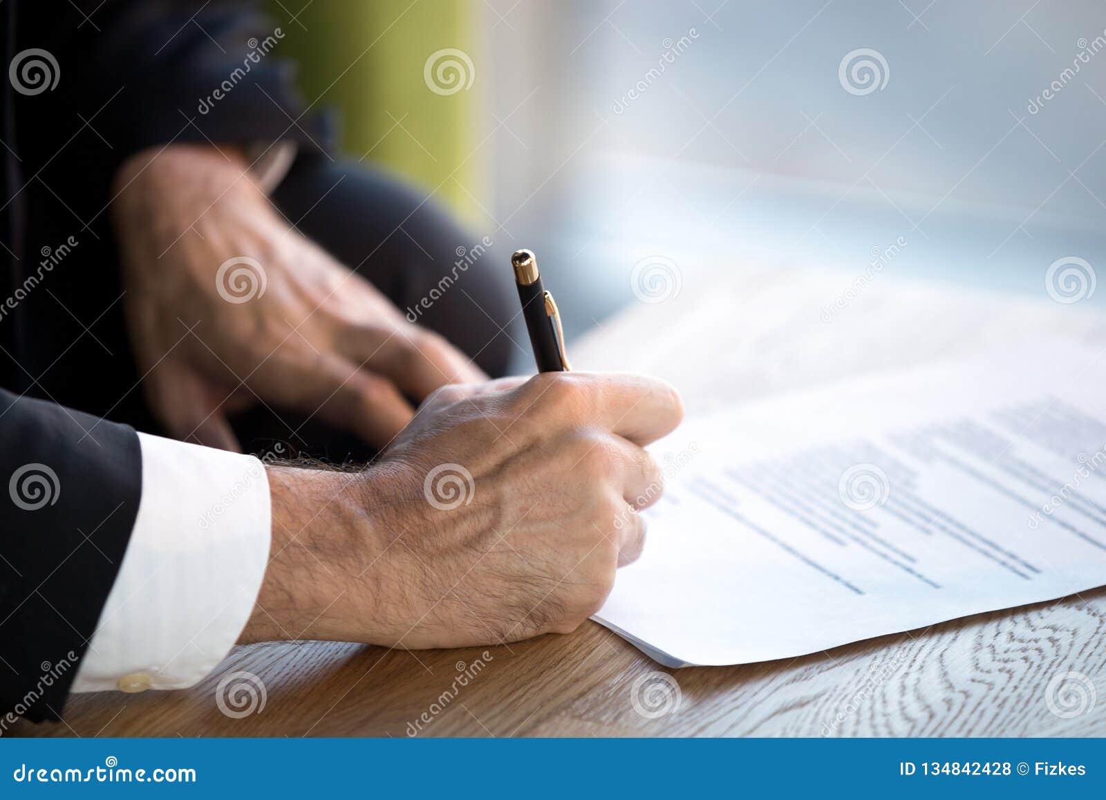 close up male hands puts his signature on official document