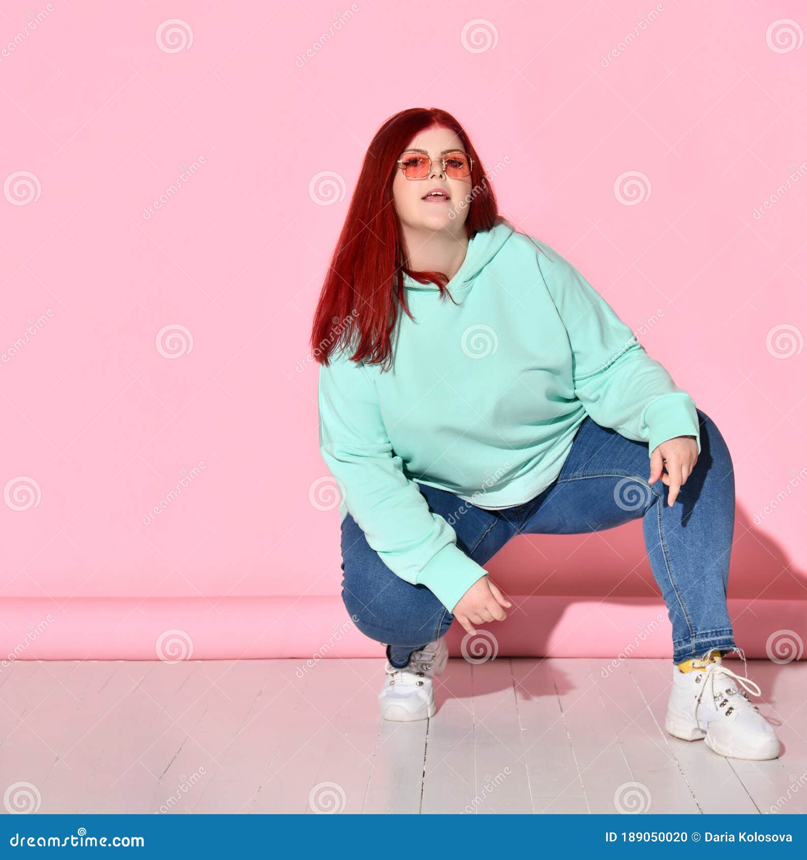 Confident Chubby Woman in Jeans, Bright Sweater and Stylish Glasses Poses  Squatting on Floor. Stock Photo - Image of fashionable, bodypositive:  189050020