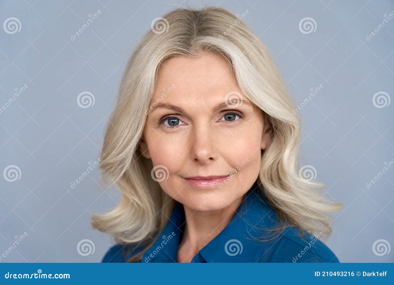 confident mid aged business woman looking at camera  on grey, headshot.