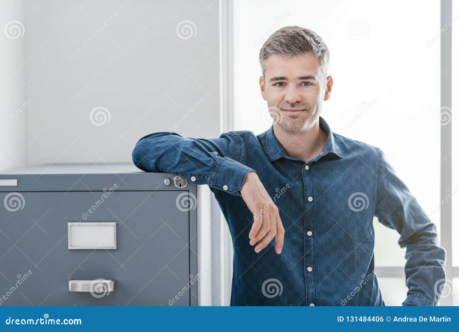 confident office worker smiling and leaning on the filing cabinet