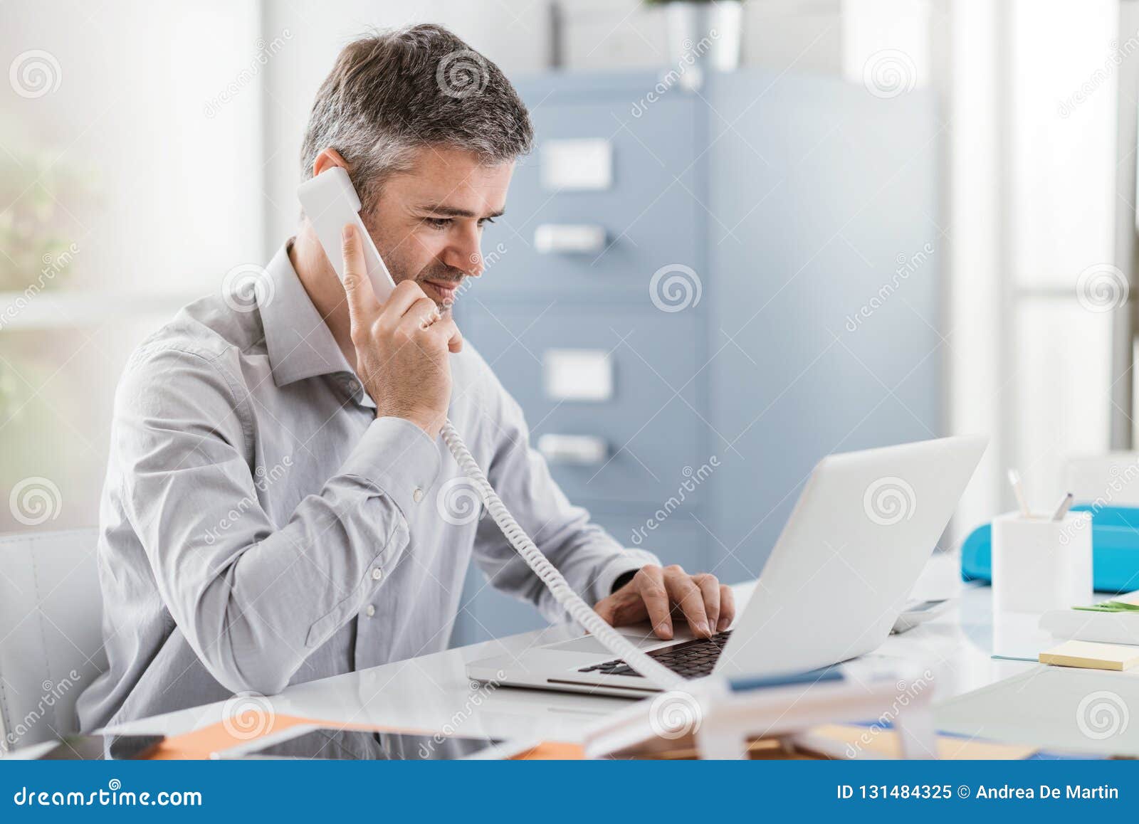 confident smiling businessman and consultant working in his office, he is having a phone call: communication and business concept