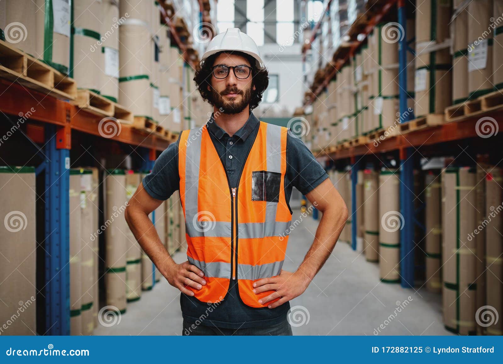 Confident Warehouse Manager Standing in between Shelf with Hands on