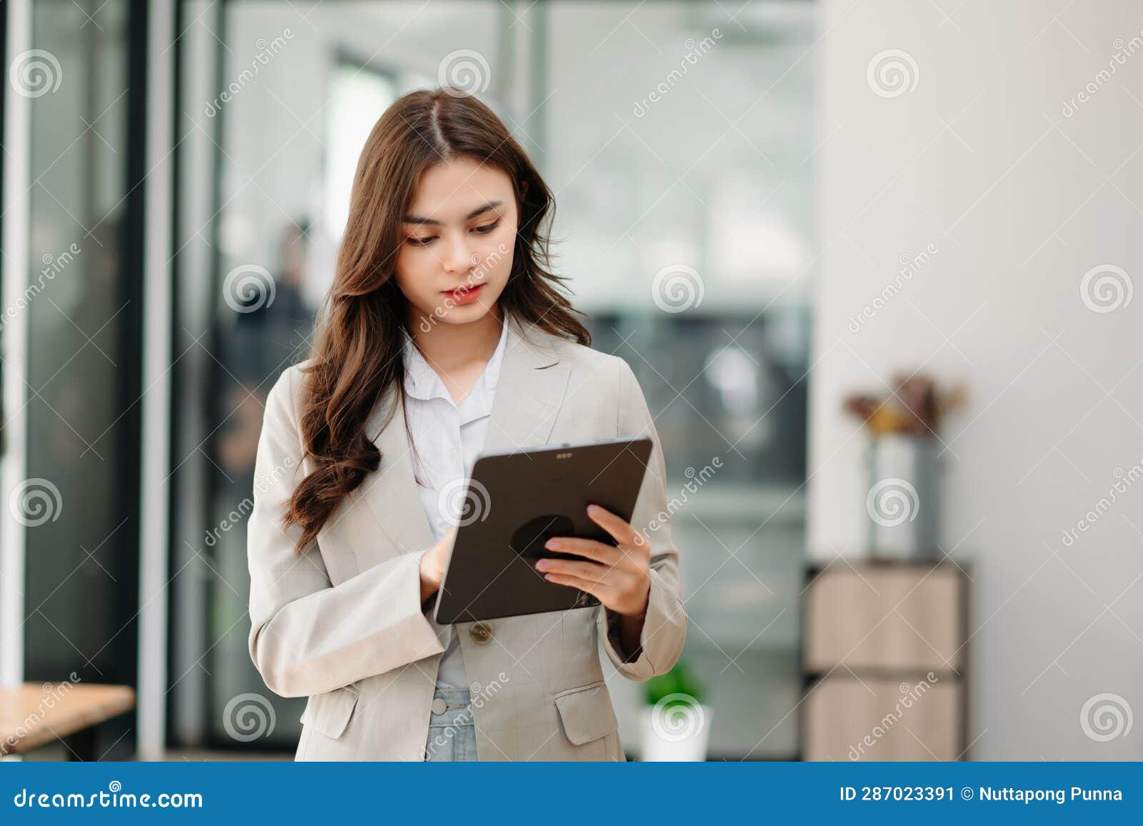 confident woman with a smile standing holding notepad and tablet at the ffice