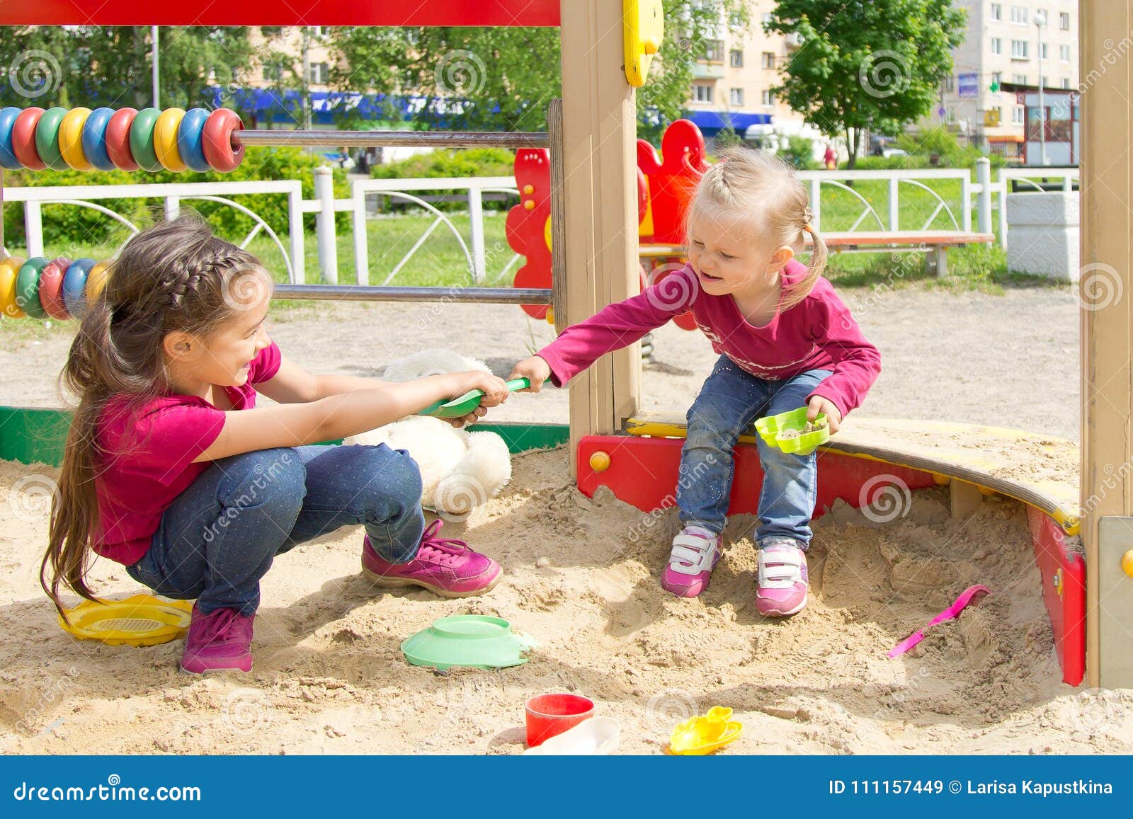 conflict on the playground. two kids fighting over a toy shovel in the sandbox