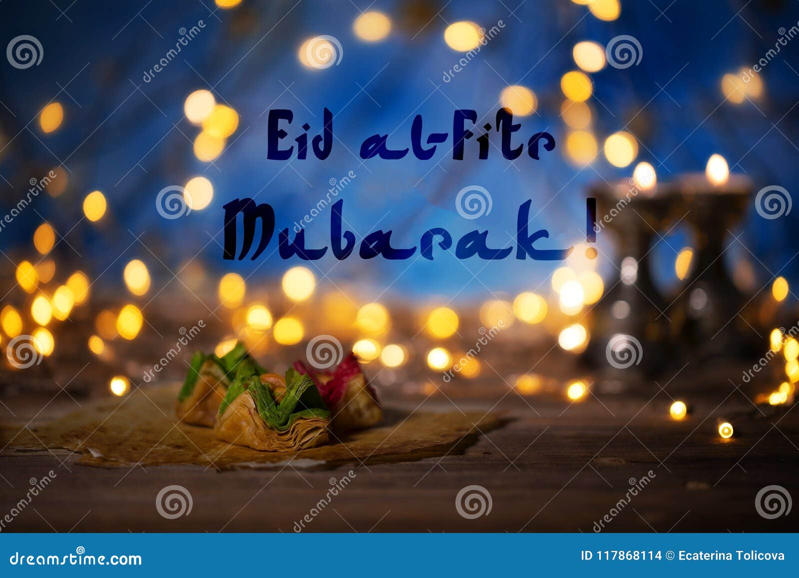 congratulation: eid al-fitr mubarak! arabic sweets on a wooden s