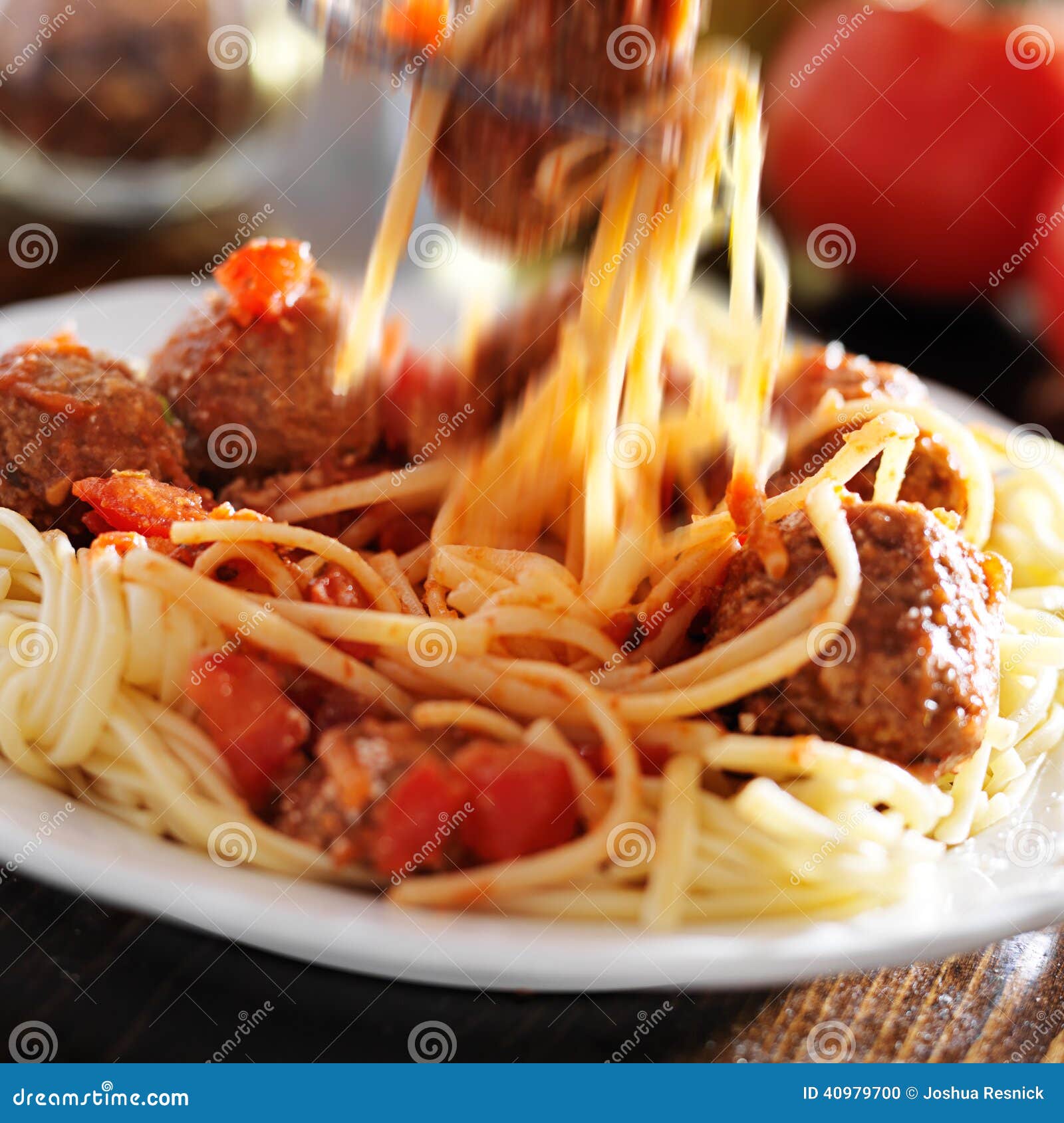 La consommation des spaghetti et des boulettes de viande avec la tache floue de mouvement évidente comme fourchette soulève les nouilles de spaghetti