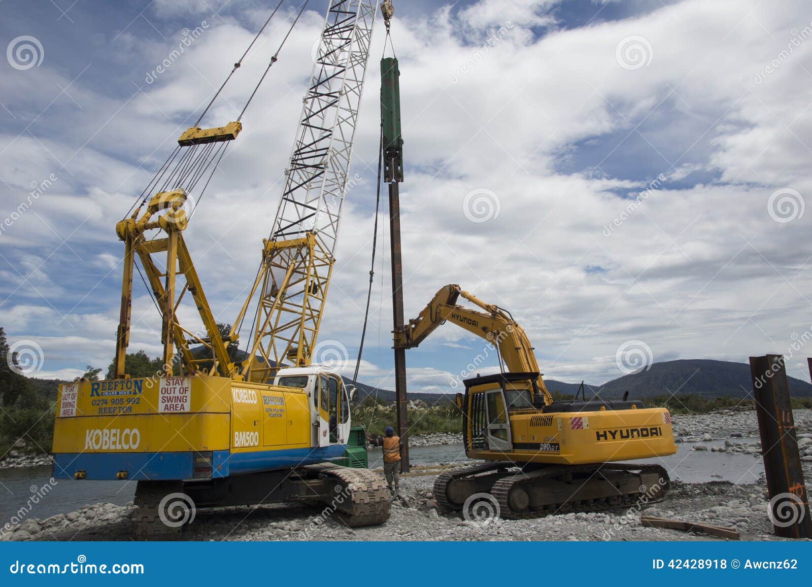 Constructeurs de pont. GREYMOUTH, NOUVELLE-ZÉLANDE, DÉCEMBRE 2013 : Les constructeurs conduisent des pylônes pour un pont concret au-dessus d'une petite rivière dans Westland, Nouvelle-Zélande