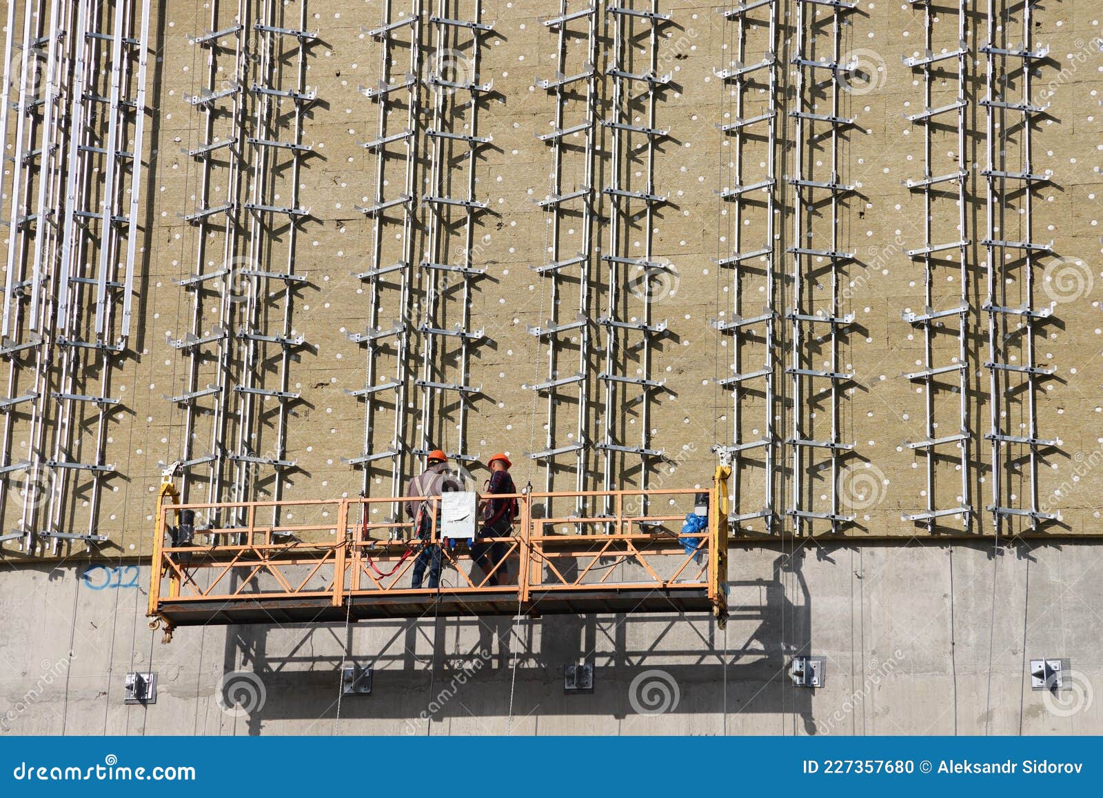 Construction Cradle with Workers on the Wall of a Building Under