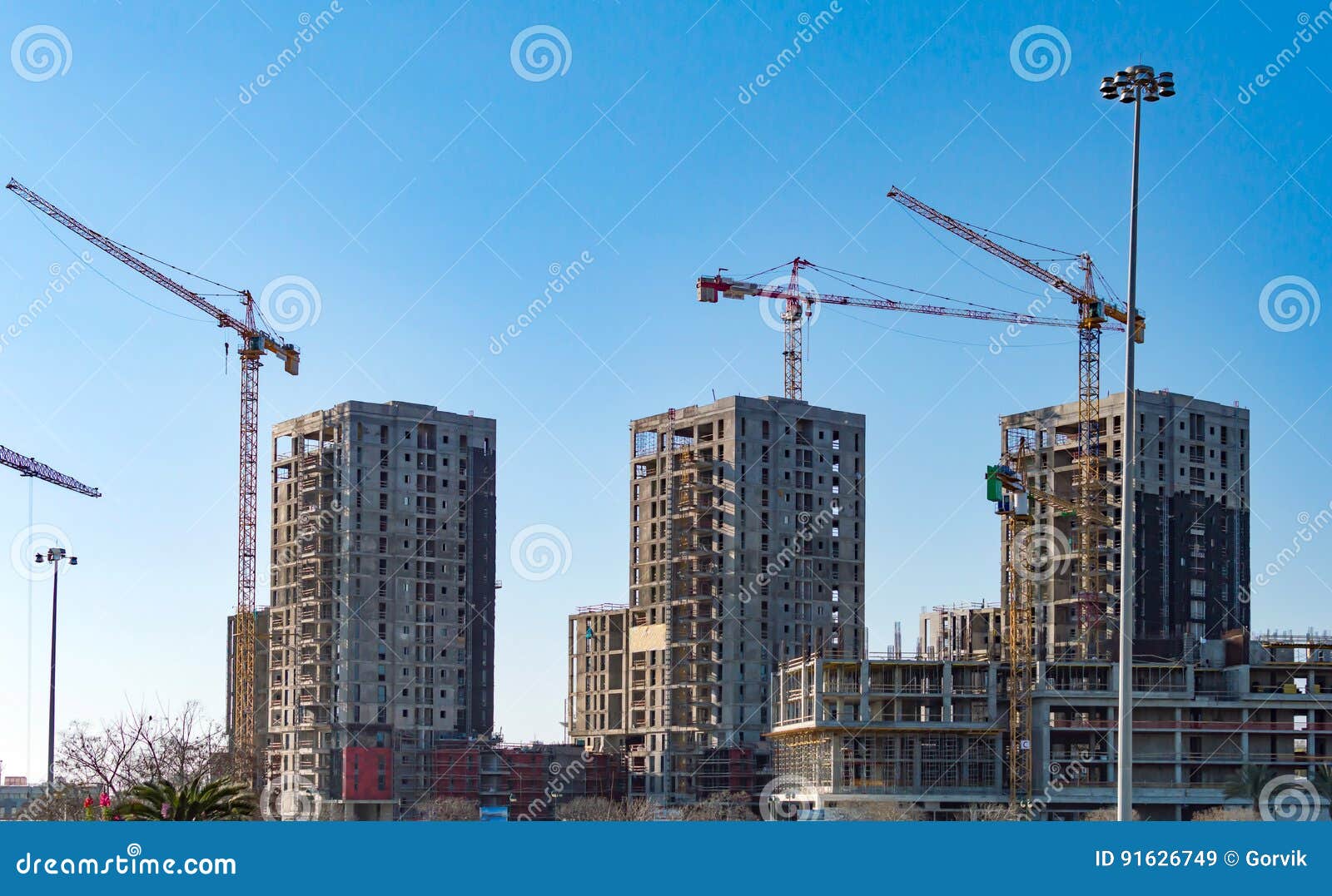 Construction cranes and tall buildings on a background of blue sky