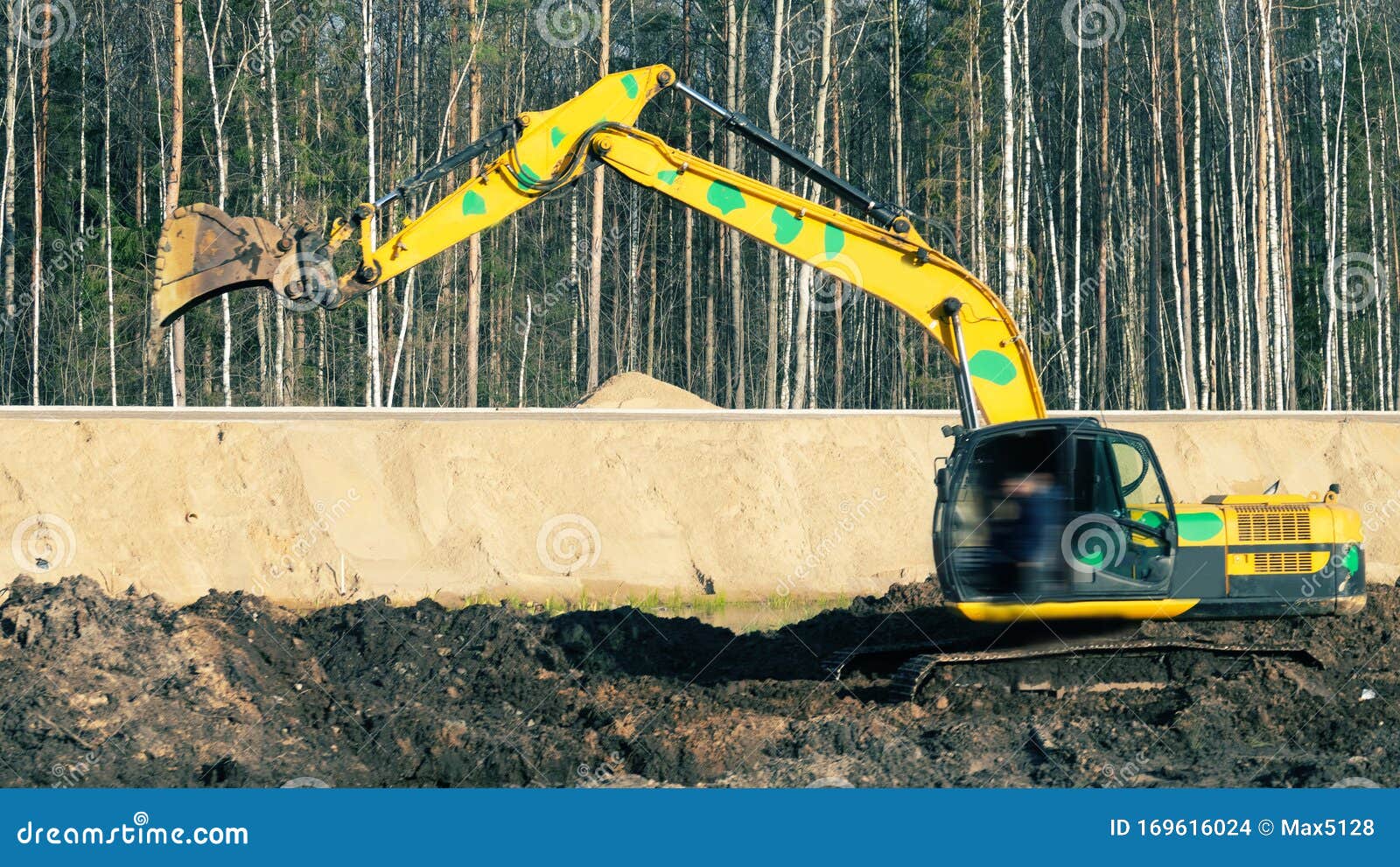 Excavator in the Process of Leveling the Slope of the Road Stock Photo