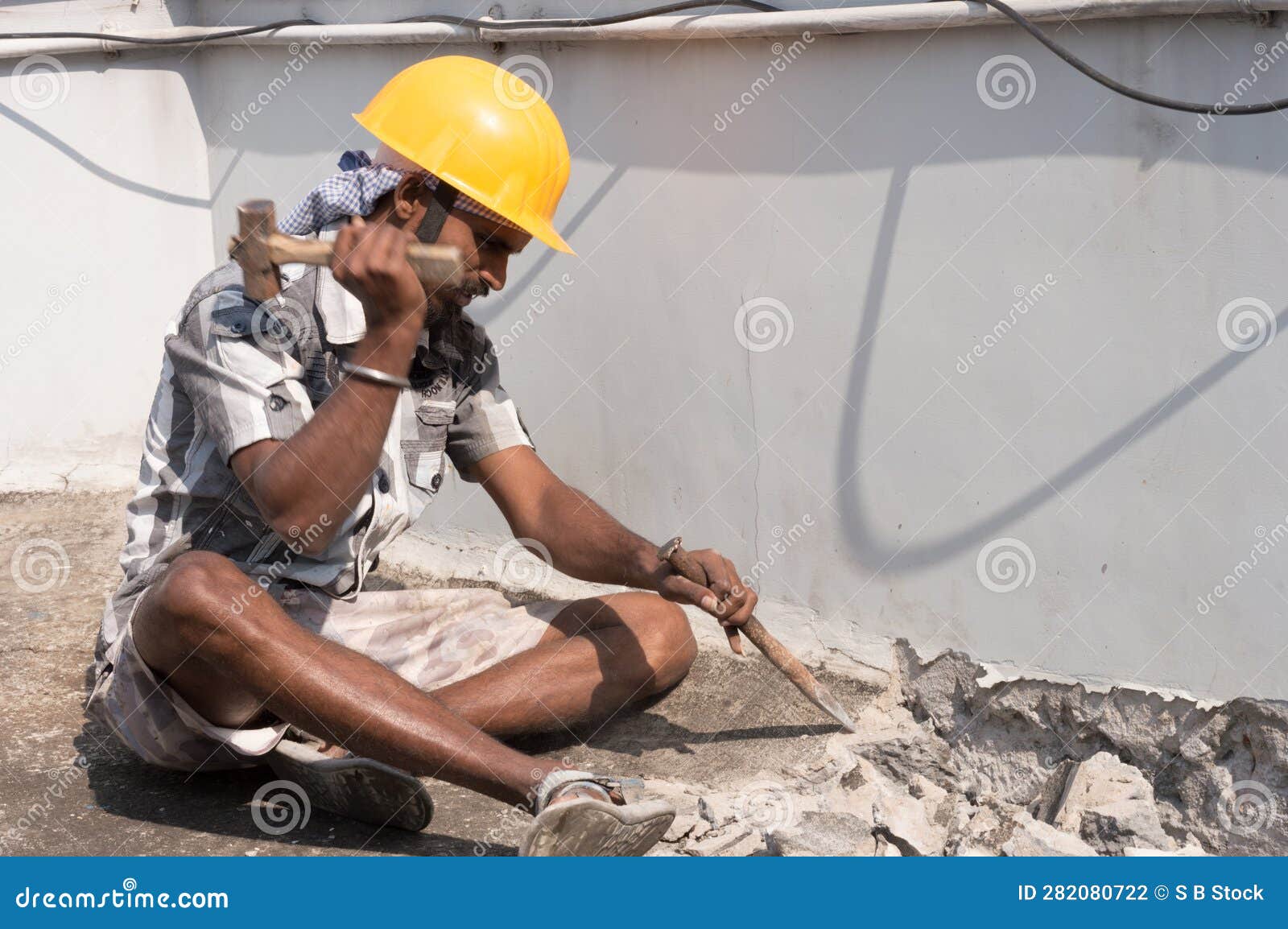 A Construction Labour Working with Hammer and Chisel Wearing Safety