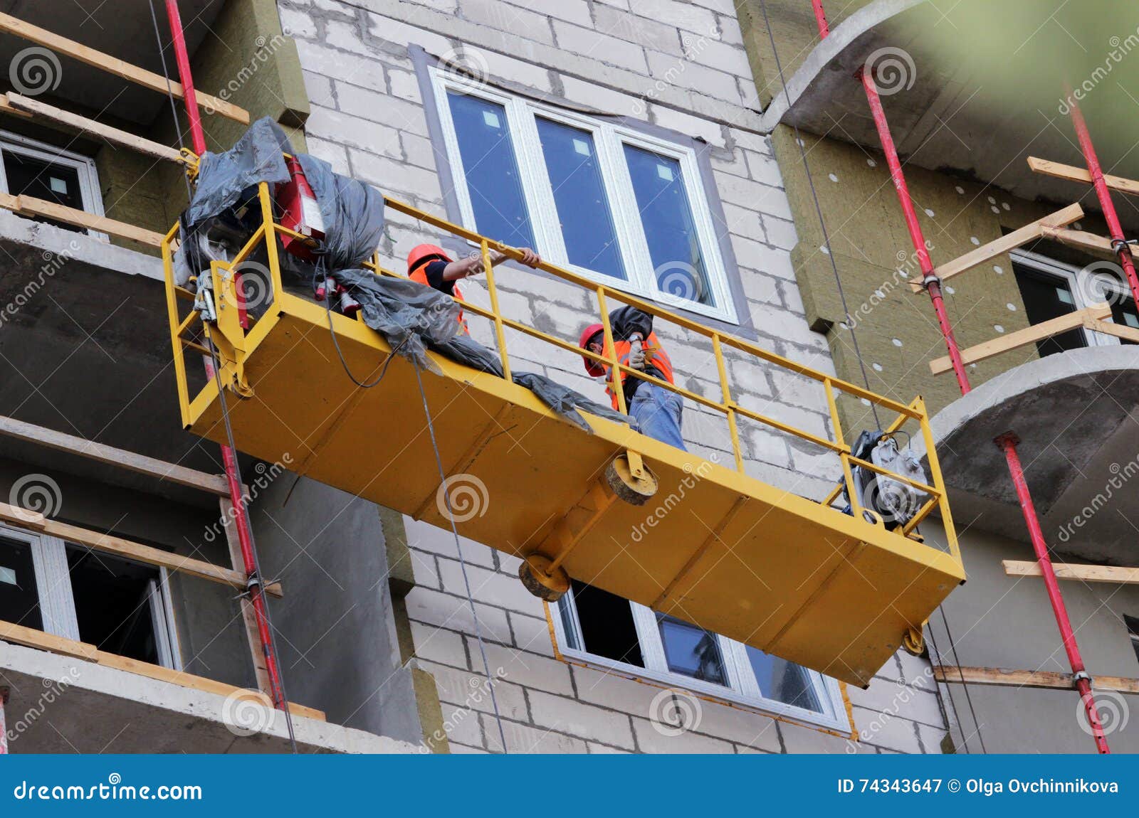 construction suspended cradle with workers on a newly built high-rise building