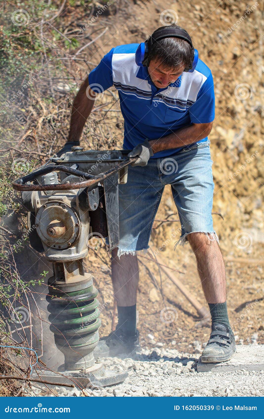 Construction Worker Compacting Soil Using Compactor. Work with Tamping