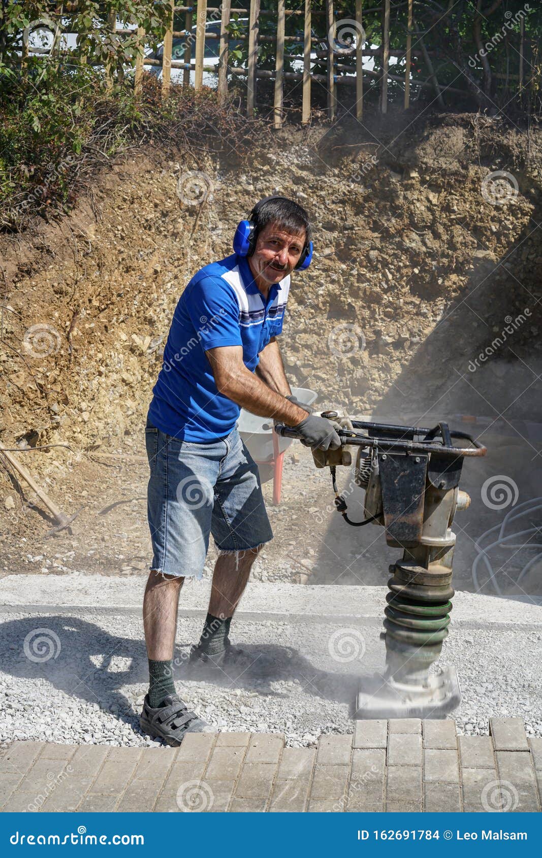 Construction Worker Compacting Soil Using Compactor. Work with Tamping Machine Stock Photo
