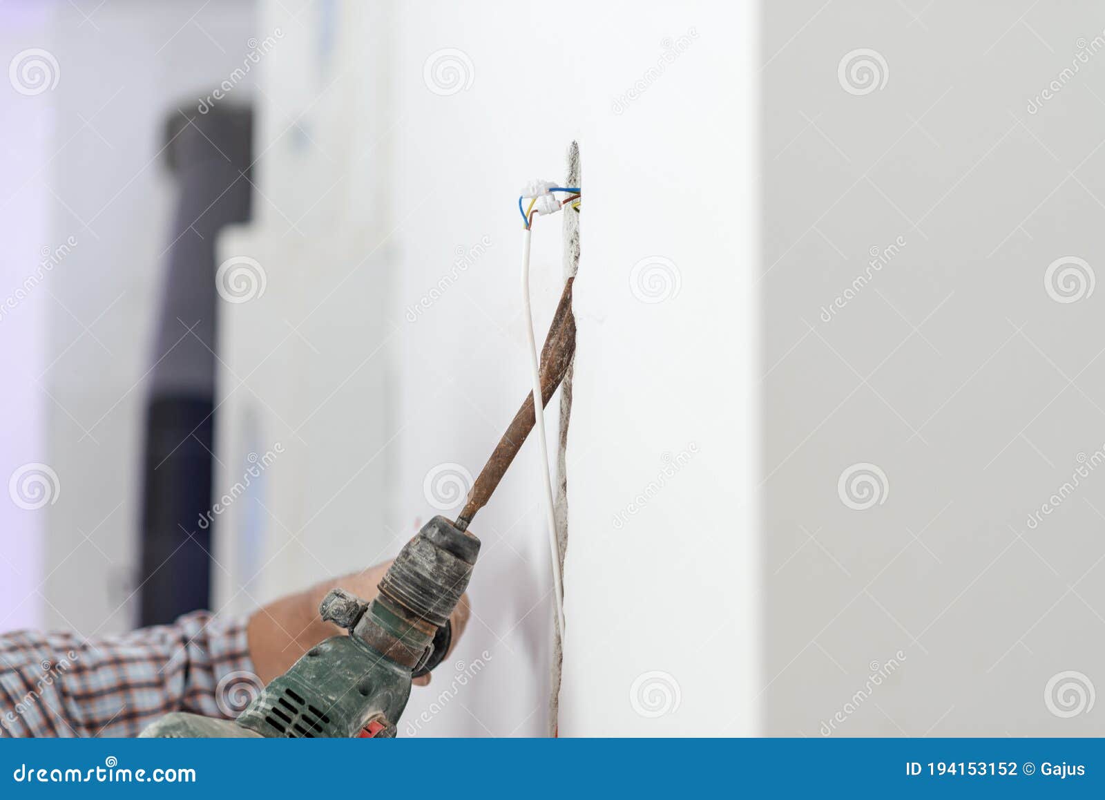 Construction Worker Drilling Hole in the Wall To Install Electrical