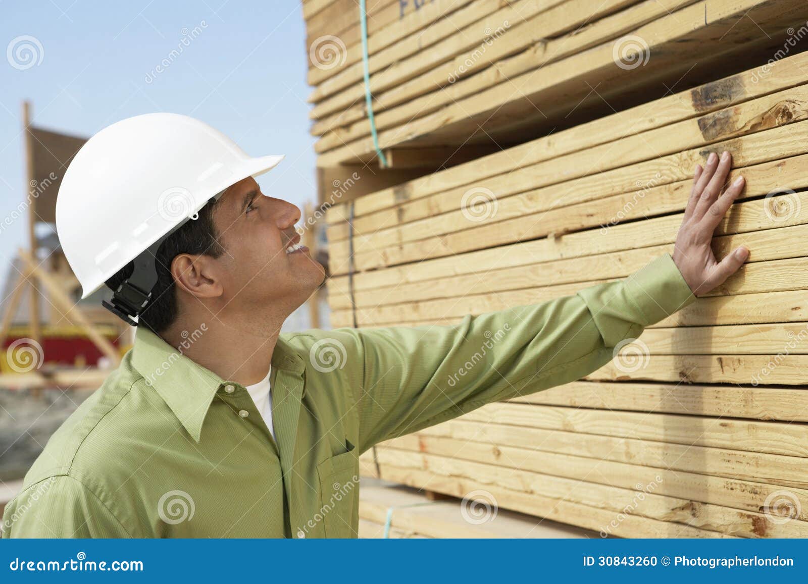 construction worker in hardhat inspecting lumber