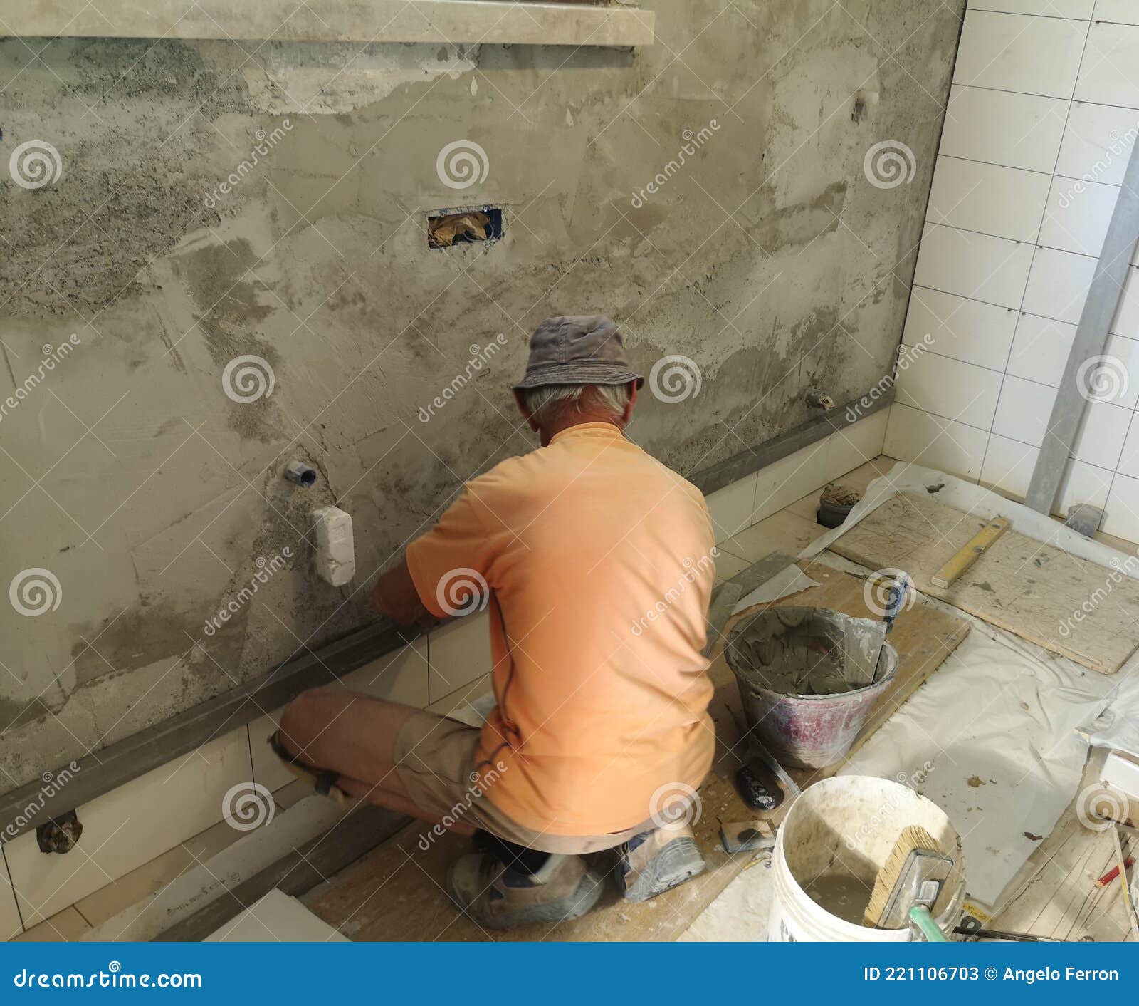 construction worker intent on remodeling the bano tiling the walls walls