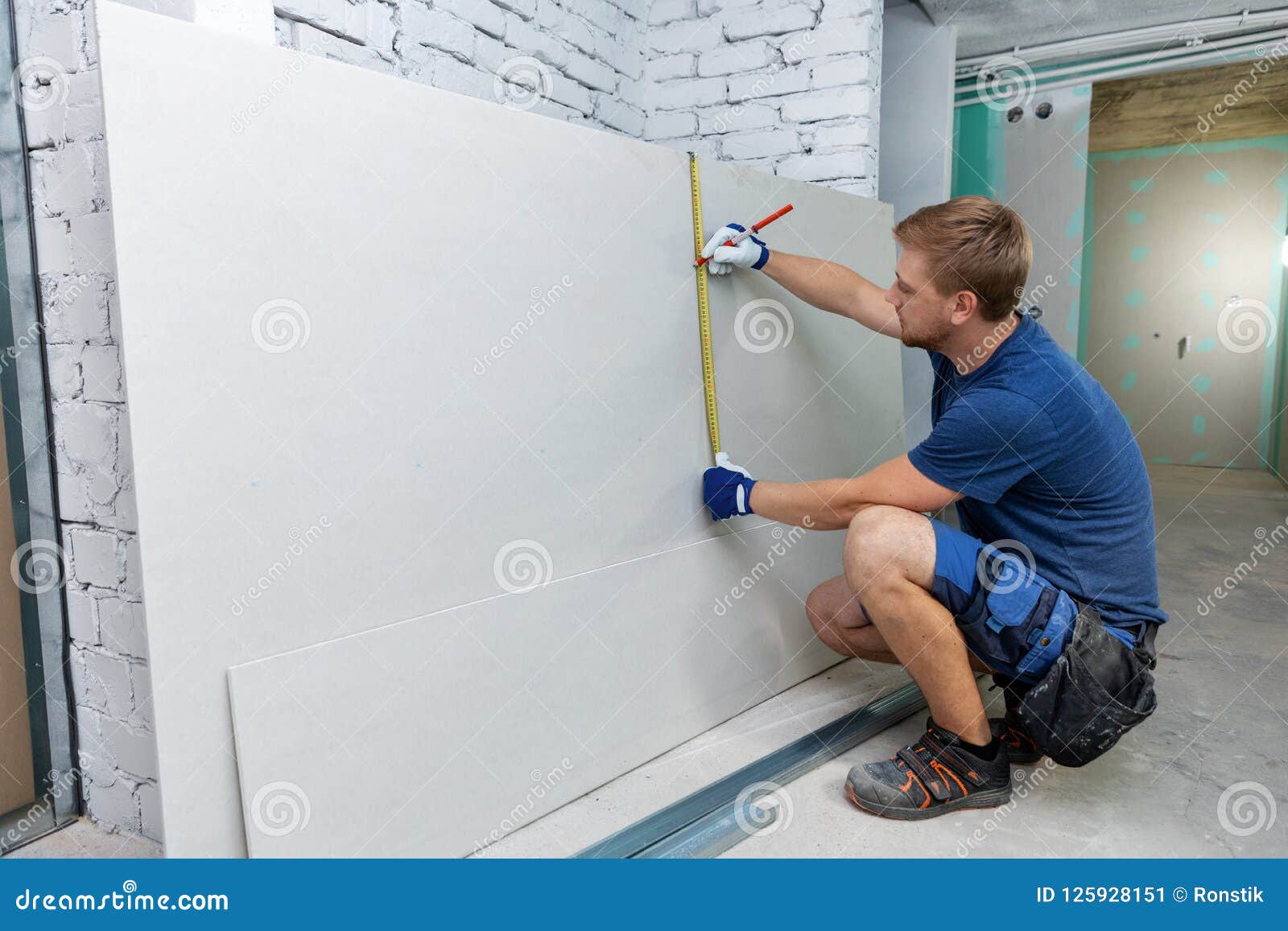 man measuring plasterboard sheet for interior construction