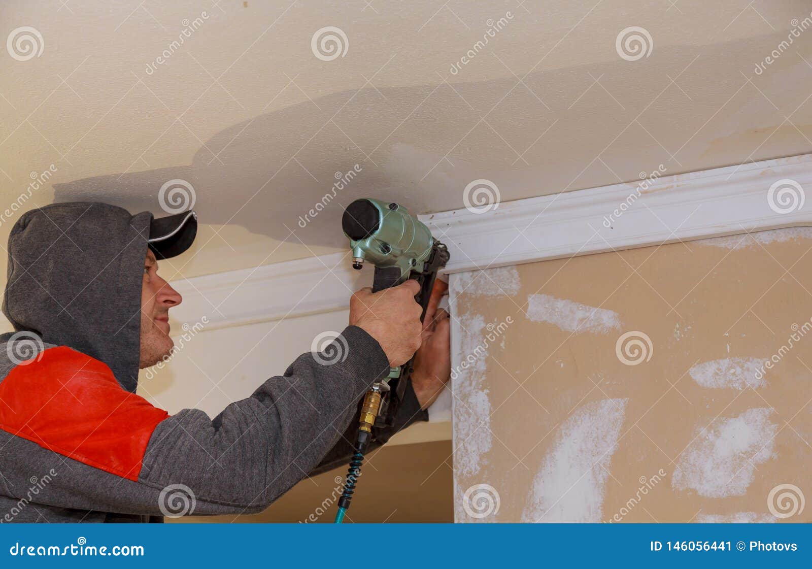 Construction Worker Nailed Up Moulding Wall in the New House Stock
